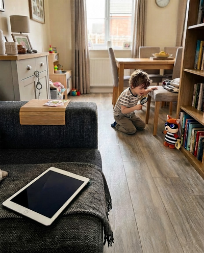 Child searching the living room with a magnifying glass while the fox bandit hides by the bookshelf