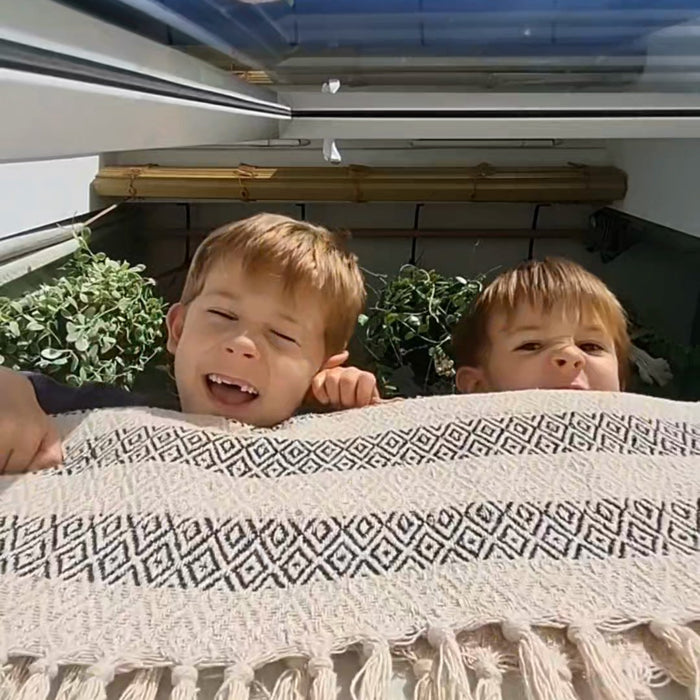 Two boys peeking over a blanket while hunting for the fox bandit