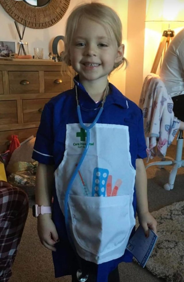 A girl at home in the nurse set, stethoscope round her neck and prescription pad in hand