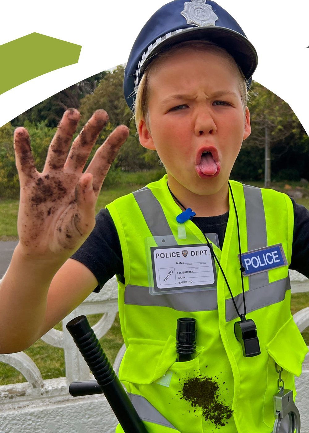Boy in the police vest holding up two muddy hands