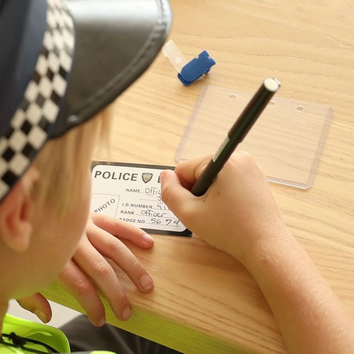 Child writing their name on the police ID card